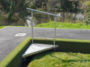 A metal ramp adjacent to a grassy area, designed for accessibility