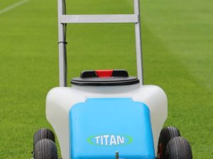 Lawnmower mowing grass on a stadium field with seats visible in the background