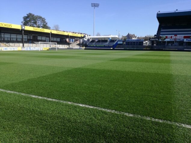 A Brief History Of The Football Pitch A vibrant football field with lush grass, surrounded by a modern stadium